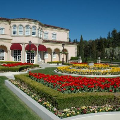 The building building has amazing garden with red and yellow flowers in front.